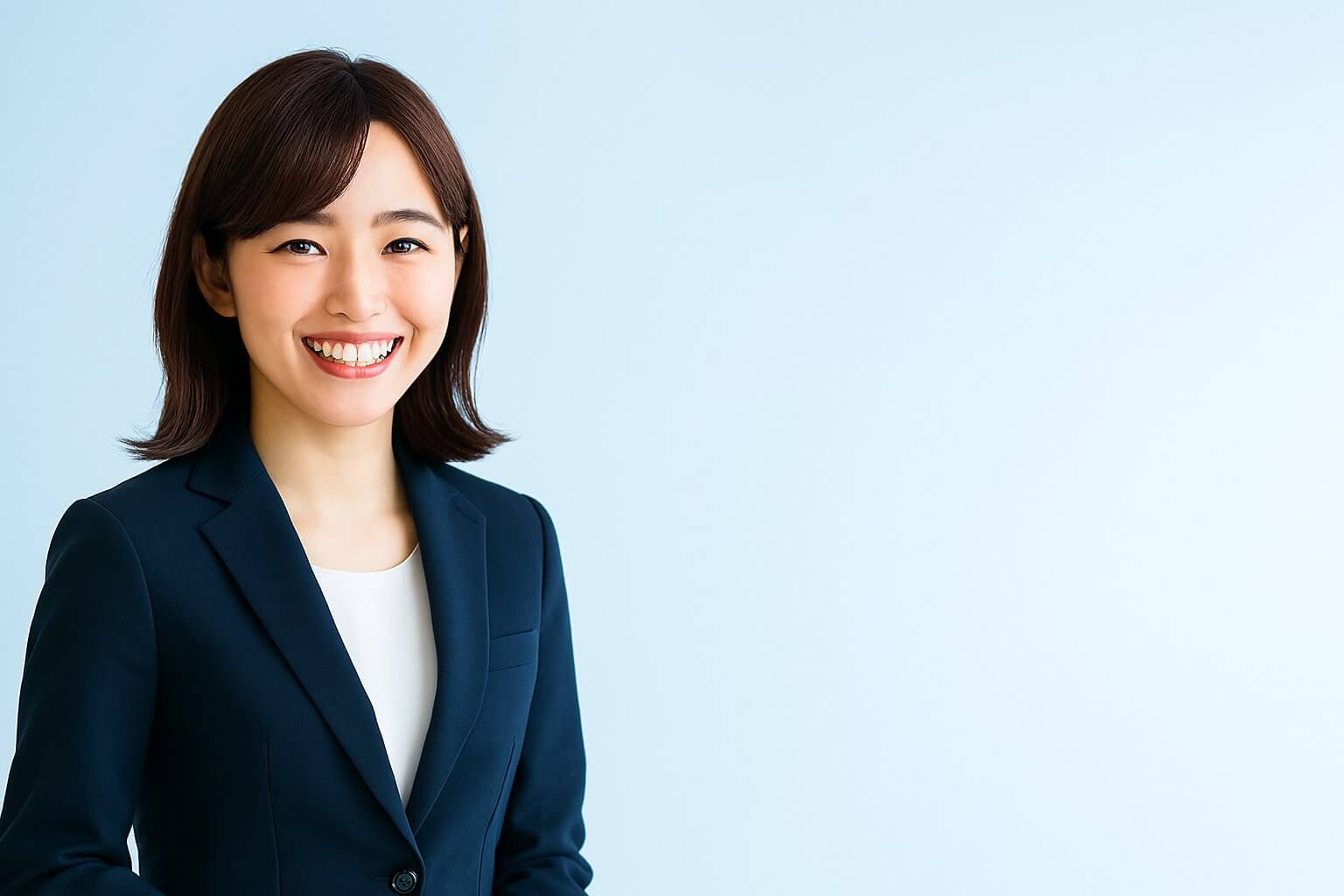 ネイビースーツを着て微笑む若手の女性。